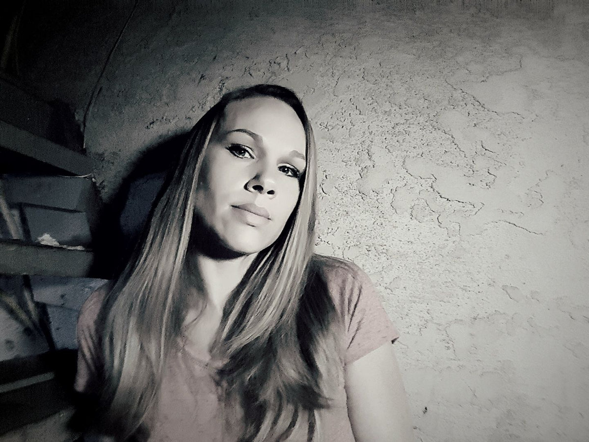 Woman with long blonde hair against a textured wall.